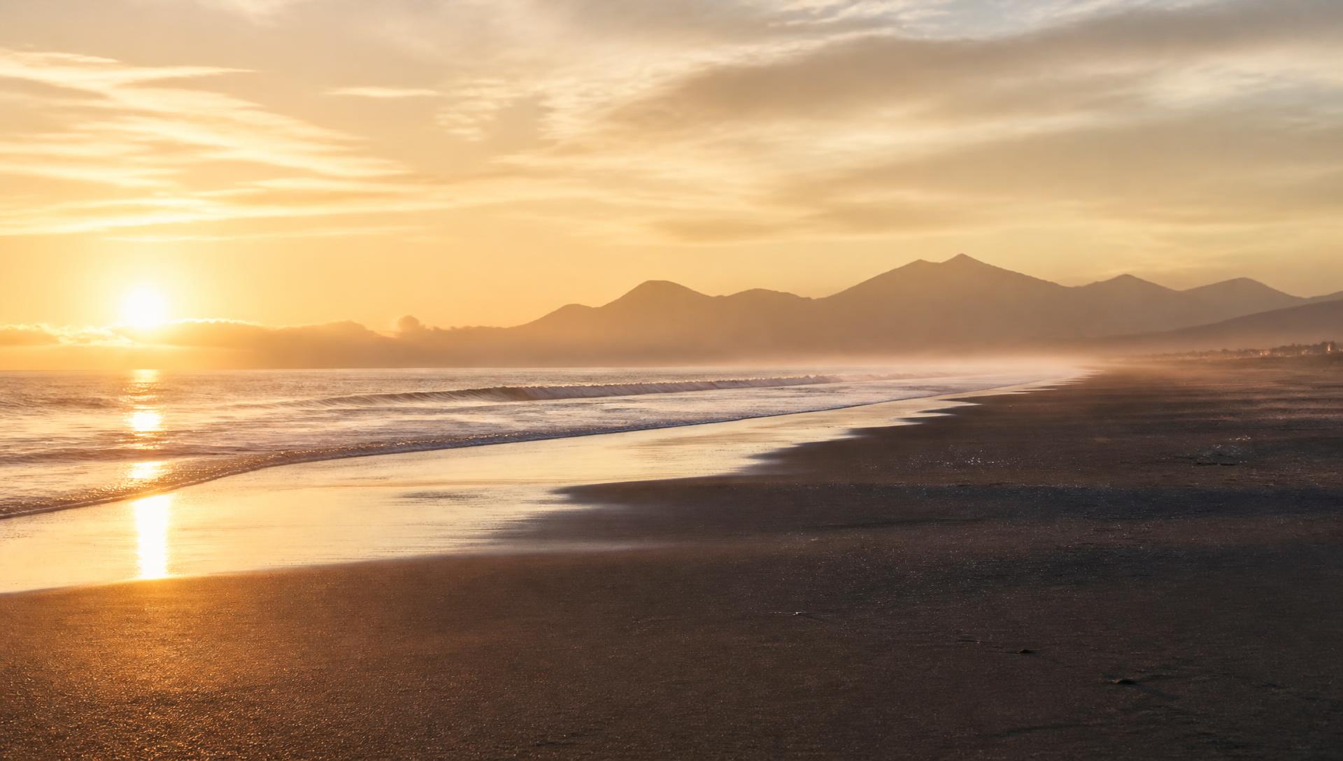 Empty coastline at sunrise with distant mountains