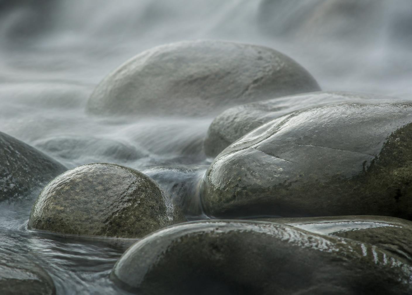 River stones under flowing water and mist
